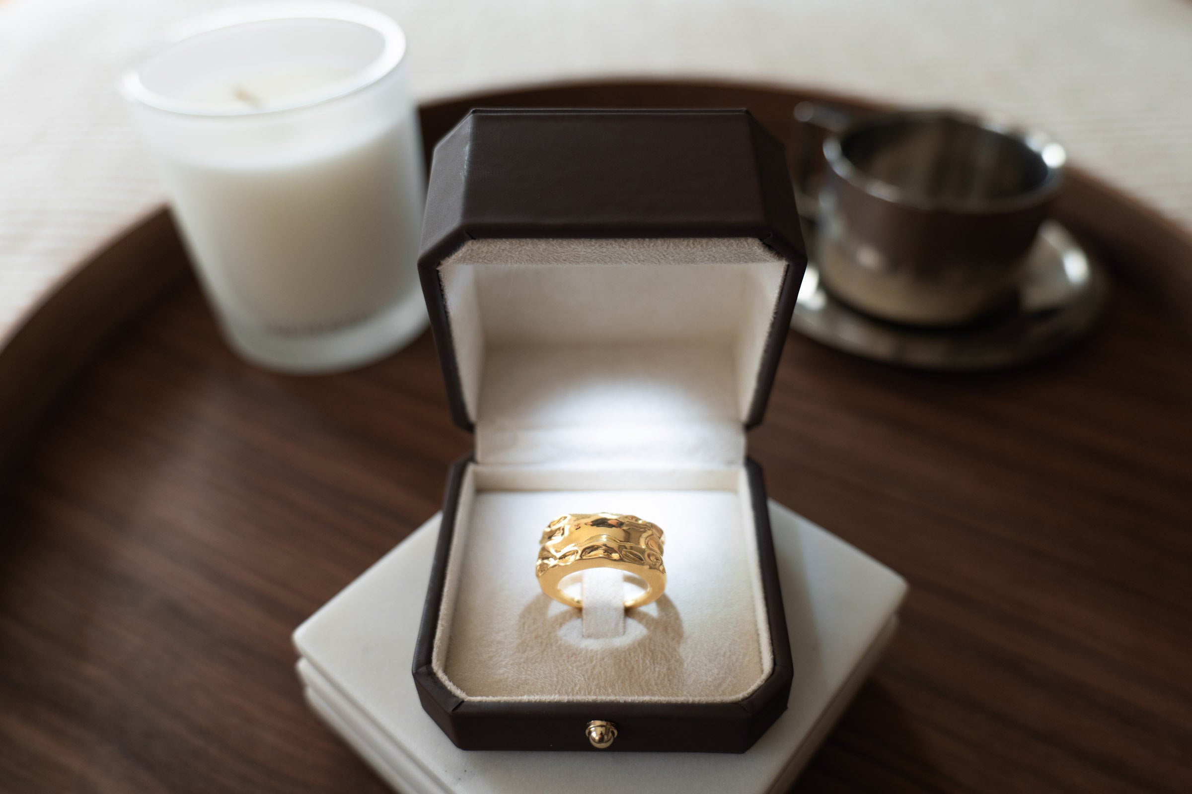 Aurean Flow Cloak gold in leather presentation box beside candle and espresso